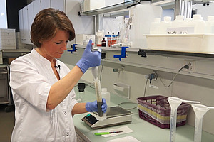 Person im Labor mit Pipette.