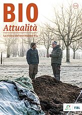 Copertina di Bioattualità 3|24: Due uomini in conversazione sono in piedi in un campo, con alberi sullo sfondo e un cumulo di compost in primo piano.